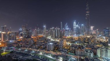 Dubai Downtown during all night with moon and lights turning off with tallest skyscraper and other illuminated towers panoramic view from the top in Dubai, United Arab Emirates.