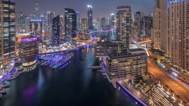 Havadan Dubai marina gökdelenleri ve kanalın etrafındaki JBR kuleleri ve gece gündüz yüzen tekneler. Günbatımından sonra beyaz tekneler yat kulübüne park edilir.