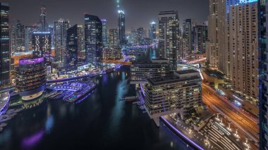 Panorama Dubai marinasının hava manzarasını gösteriyor. Kanal çevresindeki gökdelenler yüzen yatlarla aydınlatılıyor. Jlt ve JBR bölgelerindeki kuleler. Yat kulübünde beyaz tekneler var.