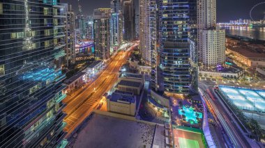 Panorama showing Dubai Marina and JBR area and the famous Ferris Wheel aerial night and illuminated skyscrapers and traffic on streets