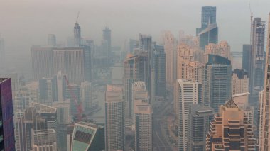 Dubai Marina 'nın Vew' ı gece gündüz kıyı şeridi boyunca aydınlık gökdelenlerle çevrili kanalı gösteriyor. Güneş doğmadan önce yüzen yatlar ve tekneler. Dubai, BAE