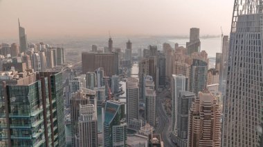 Dubai Marina 'nın Skyline panoramik görüntüsü kıyı şeridi boyunca gökdelenlerle çevrili yapay bir kanalı gösteriyor. Bütün gün boyunca gölgeler hızla hareket ediyor. Yüzen yatlar ve tekneler. Dubai, BAE