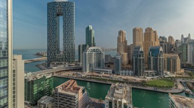 Panorama showing Dubai Marina with boats and yachts parked in harbor and skyscrapers around canal aerial morning during sunrise. Towers of JBR district on a background