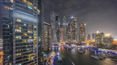 Dubai marinası güneş battıktan sonraki gece limanında parlayan pencereleri ve yatları olan en uzun gökdelenler. Apartman binalarına, otellere ve ofis bloklarına, BAE 'nin modern yerleşim alanlarına bak