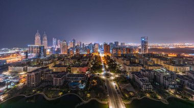 Barsha Heights bölgesindeki gökdelenlerin panoraması ve tüm gece boyunca Yeşiller semtindeki alçak binaların panoraması. Işıklar sönerken Dubai silueti