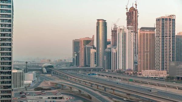 迪拜码头摩天大楼和谢赫扎耶德公路与地铁铁路的空中过渡 阿拉伯联合酋长国日出前靠近现代塔楼的高速公路上的交通情况 — 图库照片