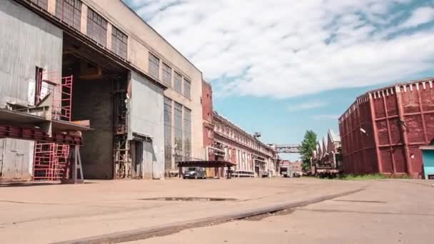門のある古い工場の店の建物は 過経過を示します アスファルト上のレールと大きな工場の工業地帯での建物のビュー — ストック動画