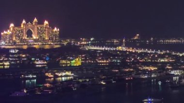 Dubai Marina 'dan gece vakti Palm Jumeirah' a hava görüntüsü. Lüks oteller ve villalar aydınlatılmış.