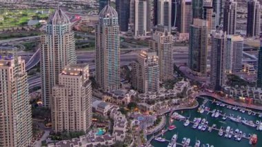 Dubai Marina 'da yatlar ve gece gündüz hava geçiş zamanı. Mavi gökyüzü ile açık bir akşamda parlak ışıklar ve en yüksek gökdelenler. Gün batımından sonra yukarıdan görünüm