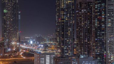 Modern mimari zaman çizelgesi olan Business Bay bölgesi ufuk çizgisi. Dubai gökdelenlerinin hava manzarası ve ana karayolu yakınında parlayan pencereleri olan aydınlık kuleler. Yol ayrımında trafik