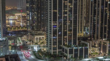 Çeşmeli Dubai şehir merkezi trafiğinin havadan görüntüsü ve birçok ışıklandırılmış kule gece zaman dilimi. Akıllı şehir şehrindeki iş alanı. Gökdelen ve yüksek binalar yukarıdan, BAE.