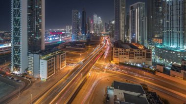Fütürist kuleleri ve aydınlatılmış gökdelenleri olan hızlı karayolu kavşağı. Dubai şehir merkezi ve finans bölgesinde trafik vardı. Şehir silueti gökyüzü gece zaman çizelgesi yukarıdan.