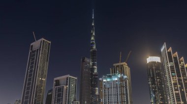 Hava görüntüsü Dubai şehir merkezinin ufuk çizgisine bakıyor. Gece vakti aydınlatılmış pek çok kulenin olduğu yere. Akıllı şehir şehrindeki iş alanı. Gökdelen ve yüksek binalar yukarıdan, BAE.