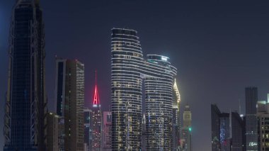 Dubai şehir merkezi ve finans bölgesinde pencereleri ışıklandırılmış fütüristik kuleler ve aydınlık gökdelenler. Urban City Ufuk Çizgisi Hava Gecesi Zaman Çizgisi. Karanlık gökyüzü