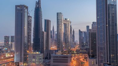 Dubai şehir merkezi ve finans bölgesindeki caddelerde trafiği olan gelecekçi kuleler ve gökdelenler. Şehir silueti gece gündüz gökyüzü geçiş zamanı gün doğumundan önce.