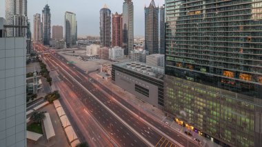 Business Bay bölgesinin ufuk çizgisi gece gündüz modern mimari geçiş zamanı yukarıdan. Güneş doğmadan önce ana karayolu yakınlarındaki Dubai gökdelenleri ve kulelerinin hava manzarası. Yol ayrımında trafik