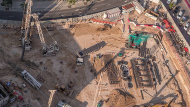Vinç, kamyon ve buldozerle toprak hareket etmek için ağır makineler. Yeni gökdelen zaman ayarlı bir temel çukuru olan hava manzaralı bir inşaat alanı. Toprak kazısı ve toprak dolumu alanındaki toprak çalışmaları.