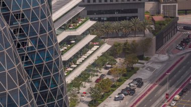 Gökdelen zaman diliminin açık terasındaki rahat restoranların havadan görünüşü. Dubai 'nin finans bölgesinde masalarda oturan insanlar. Otomobiller girişe yakın.