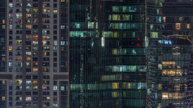 Ofis ve konutların pencereleri gece vakti aydınlatılıyor. Cam mimari, şirket binası, parlayan ışıklar.