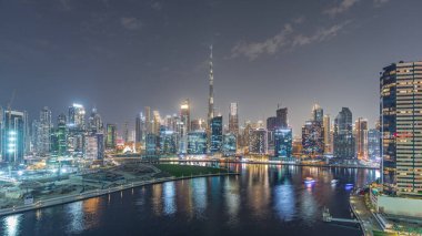 Dubai Business Bay ve şehir merkezinin havadan görüntüsü. Kanal boyunca çeşitli gökdelenler ve kuleler var. Vinçli inşaat alanı