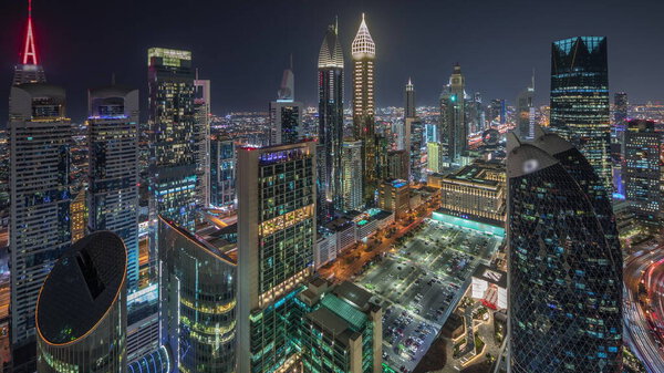 Skyline view of the high-rise buildings on Sheikh Zayed Road in Dubai aerial night timelapse, UAE. Illuminated skyscrapers in International Financial Centre from above. Parking near shopping avenue