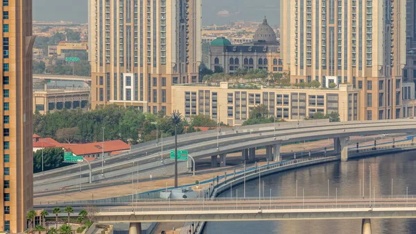 ドバイ航空のタイムラプスのビジネスベイ地区のカフェやレストランで運河沿いの遊歩道を歩く 上から高層ビルでウォーターフロントに架かる橋 アラブ首長国連邦 — ストック写真
