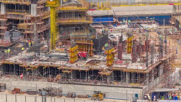 作業クレーンのタイムラプス付きの大規模な建設現場 ドバイのビジネスベイに多くの労働者と住宅やオフィス街の大規模な開発のトップの航空機のクローズアップビュー — ストック写真