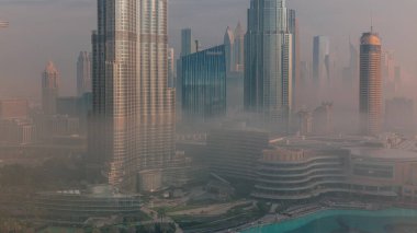 Sabahın erken saatlerinde Dubai sehrinin sisli görüntüsü. Gökdelenler ve gökdelenlerle dolu fütüristik şehir siluetinde gün doğumu. Güneş cam yüzeyden yansıyor