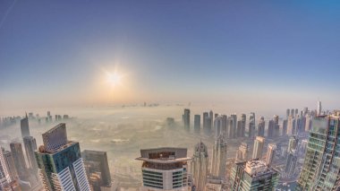 Dubai Marina Panoraması 'nda güneş doğarken JLT gökdelenleri ve golf sahası, Dubai, Birleşik Arap Emirlikleri. Yukarıdan hava manzarası sisli bir sabah. Çatıları olan şehir silüeti