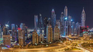 Dubai Marina 'nın gökdelenleri tüm gece boyunca ışıklandırılmış en yüksek konut binaları ve ışıkları kapalı. JLT bölgesinden hava görüntüsü. Otoyolda trafik vardı.