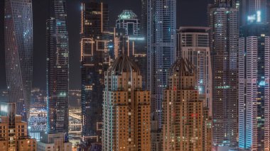 Dubai Marina 'nın gökdelenleri tüm gece boyunca en yüksek konut binalarında yanıp sönen pencereler. JLT bölgesinden hava üst görünümü