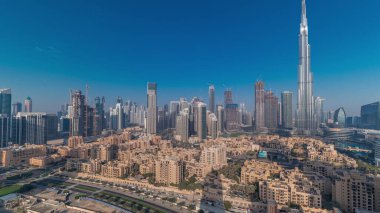 Güneşin en yüksek gökdelenden ve diğer gökdelenlerden yansıdığı Dubai Şehir Sabah Panoraması gündoğumu sırasında uzun gölgelerin hızlı hareket ettiği Birleşik Arap Emirlikleri ile tepeden görülüyor. Geleneksel evler