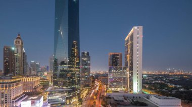 Dubai Uluslararası Finans Bölgesi, günden geceye geçiş zamanı. Gün batımından sonra panoramik ofis kulesi manzarası. Şehir merkezine yakın bir yolda otelleri ve trafiği olan gökdelenler.