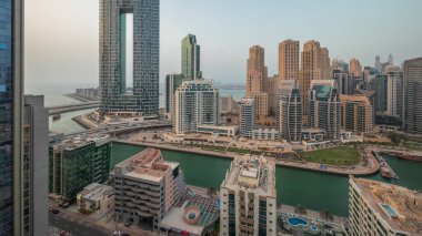 Panorama, Dubai Marina 'yı limana park etmiş birkaç tekne ve yatla ve kanalın çevresindeki gökdelenlerle gösteriyor. Arka planda JBR bölgesi kuleleri