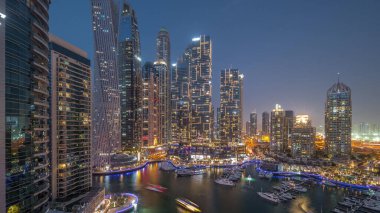 Dubai marinası en uzun gökdelenler ve yatlar limandaki gece panoramik zaman diliminde gün batımından sonra. Apartman binalarına, otellere ve ofis bloklarına, BAE 'nin modern yerleşim alanlarına bak