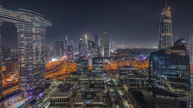 Panorama fütüristik Dubai şehir merkezini ve finansal bölge siluetini gösteriyor. Birçok aydınlık kule ve gökdelenler caddelerde trafik var.