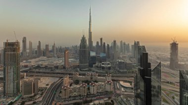 Panorama showing aerial view of tallest towers in Dubai Downtown skyline and highway before sunset. Financial district and business area in smart urban city. Skyscraper and high-rise buildings