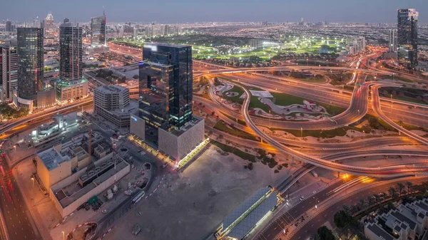 Huge highway crossroad junction between JLT district and media city intersected by Sheikh Zayed Road aerial night timelapse after sunset. Golf course near towers and skyscrapers with busy traffic