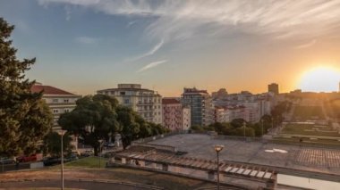 Panorama Alameda Dom Afonso Henriques 'deki çimlerin üzerinde gün batımını renkli binalar ve Aydınlık Çeşme hava saatleriyle gösteriyor. Lizbon, Portekiz 'de akşam gökyüzü ile yukarıdan görünüm