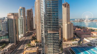 Panorama showing Dubai Marina and JBR area and the famous Ferris Wheel aerial and golden sand beaches in the Persian Gulf during sunrise