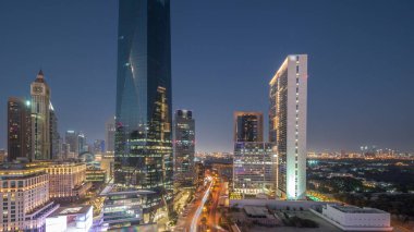 Dubai Uluslararası Finans Bölgesi, günden geceye geçiş. Gün batımından sonra panoramik ofis kulesi manzarası. Şehir merkezine yakın bir yolda otelleri ve trafiği olan gökdelenler.