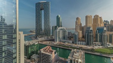 Panorama showing Dubai Marina with boats and yachts parked in harbor and skyscrapers around canal aerial morning during sunrise. Towers of JBR district on a background