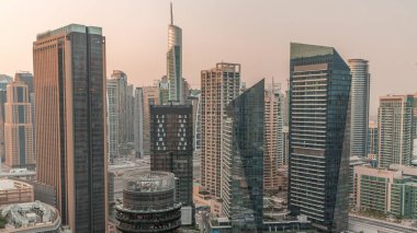 Dubai Marina Skyline ve JLT semti gökdelenleri gece gündüz arka planda. Güneş doğmadan önce cam yüzeyi olan aydınlık kuleler