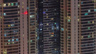 Modern kulelerin pek çok penceresinde ışık var. Geceleri parlayan pencereleri olan apartmanların dışında. Gökdelenlerin yukarıdan aydınlatmalı havadan görünüşü