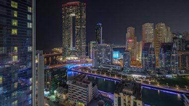 Panorama, Dubai Marina 'yı limana park etmiş birkaç tekne ve yatla ve hava kanalı etrafında aydınlık gökdelenlerle gösteriyor. Arka planda JBR bölgesi kuleleri