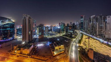 Dubai, BAE 'de gece boyunca Business Bay havacılık panoramik binasında aydınlatılmış modern kuleleri olan su kanalı. Yolunda trafik olan ve ışıkları kapanan gökdelenler.