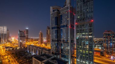 Dubai Uluslararası Finans Bölgesi 'nin tüm gece boyunca birçok gökdeleni olan havadan görüntüsü. Işıkları sönmüş kulelerle çevrili bir otoyol kavşağında trafik vardı. Dubai, BAE.