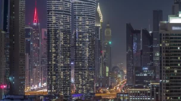 ドバイのダウンタウンや金融街の路上で交通量のある未来的なタワーや照明付き高層ビル 都市のスカイライン航空夜のタイムラプス 窓を開ける — ストック動画