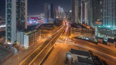 Fütürist kuleleri ve aydınlatılmış gökdelenleri olan hızlı karayolu kavşağı. Dubai şehir merkezi ve finans bölgesinde trafik vardı. Şehir silueti gökyüzü gece zaman çizelgesi yukarıdan.