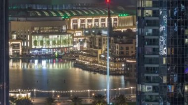 Şehir merkezindeki Dubai Çeşmesi 'nin havadan görünüşü, avuçlar ve bayraklar tüm gece boyunca alışveriş merkezinin ve Souq Timelapse' nin yanında park halinde. Yukarıdan iki gökdelen arasında ışıklar sönerken görüldü.
